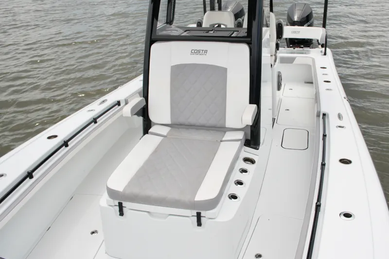 Slide: The Image of 2023 Costa Custom Boats 264 HC interior with cushioned seating on the water. - 37