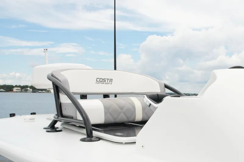 Slide: The Image of 2023 Costa Custom Boats 264 HC helm seat with scenic water backdrop. - 61