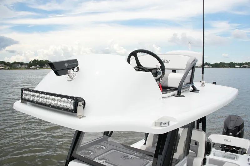 Slide: The Image of 2023 Costa Custom Boats 264 HC helm with steering wheel and light bar on water. - 59