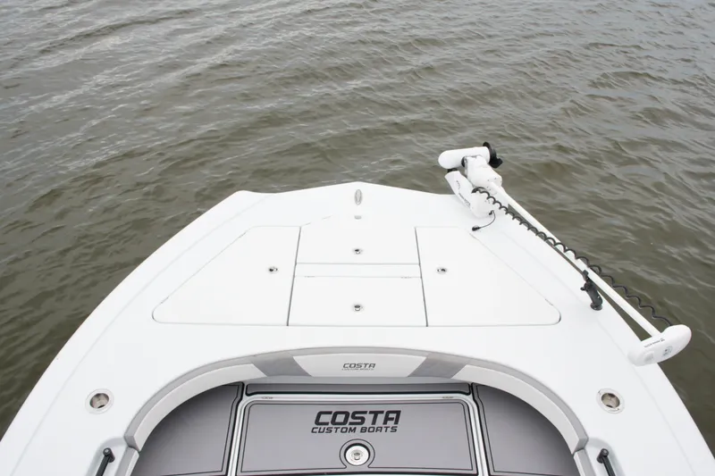 Slide: The Image of 2023 Costa Custom Boats 264 HC bow view on water, featuring sleek design and trolling motor. - 68