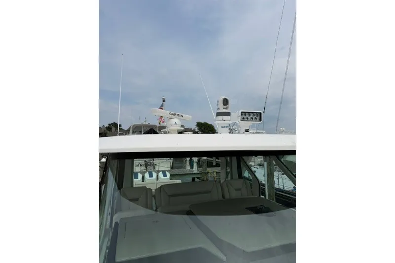 Slide: The Image of 2024 Tiara Yachts 48 LS with Garmin radar, docked under a cloudy sky. - 21