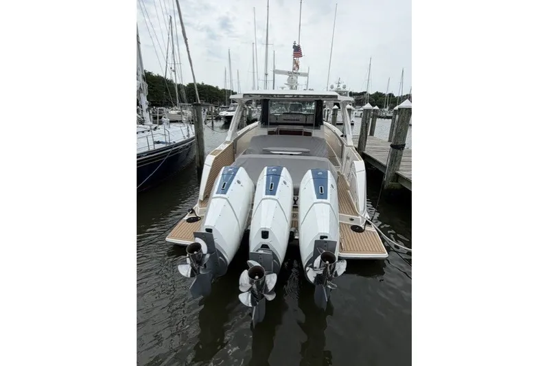 Slide: The Image of 2024 Tiara Yachts 48 LS with triple outboard engines docked at marina. - 2