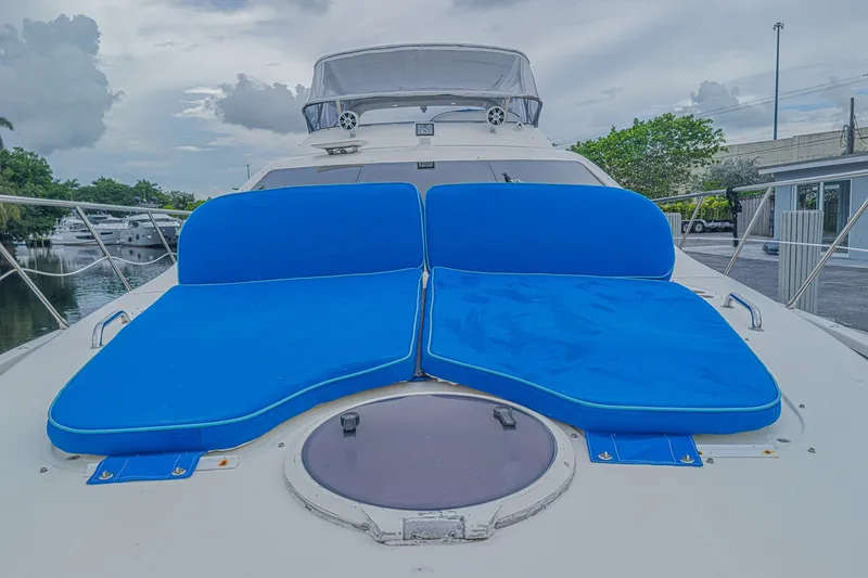 Slide: The Image of 2008 Azimut 62 yacht with blue sun loungers on deck, docked by a marina. - 64