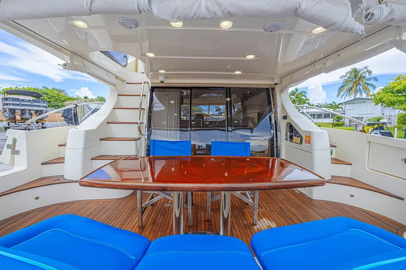 The Image of Luxurious 2008 Azimut 62 yacht deck with wooden table, blue seating, and elegant staircase. - 0