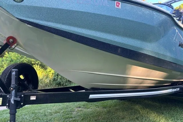 Slide: The Image of 2022 MasterCraft NXT22 boat on trailer, side view, parked on grass. - 15