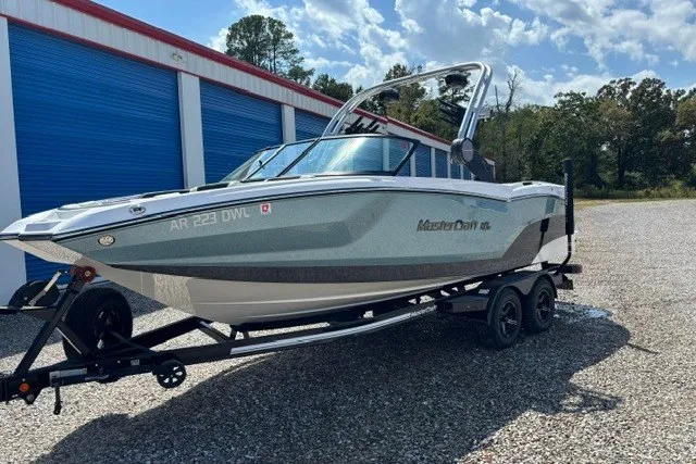 Slide: The Image of 2022 MasterCraft NXT22 boat on trailer near storage units, outdoors. - 0