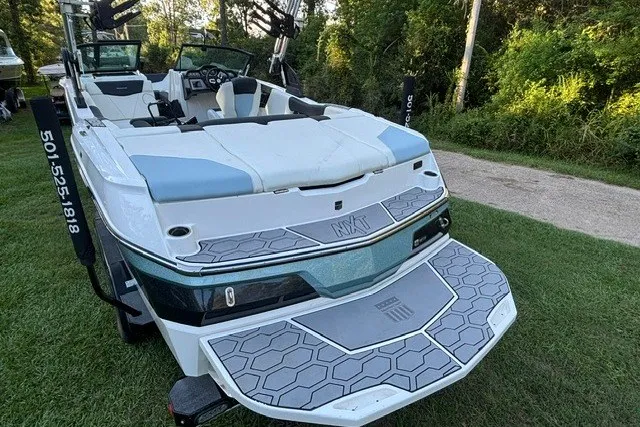 Slide: The Image of 2022 MasterCraft NXT22 boat with sleek design, parked on grass, showcasing rear deck and seating. - 16