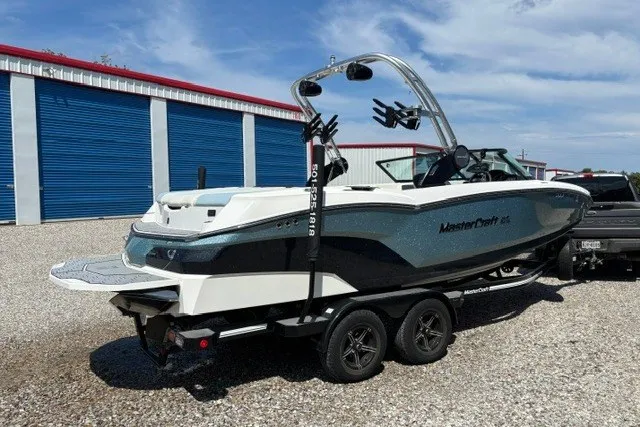 Slide: The Image of 2022 MasterCraft NXT22 boat on trailer, parked near blue storage units. - 1