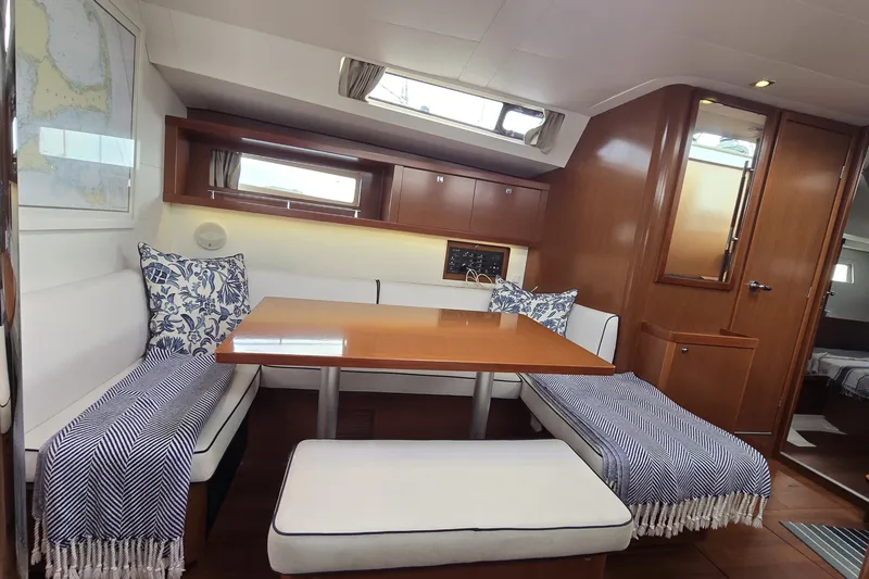 Slide: The Image of Interior of 2012 Beneteau Oceanis 45 yacht with cozy dining area and wooden finishes. - 13