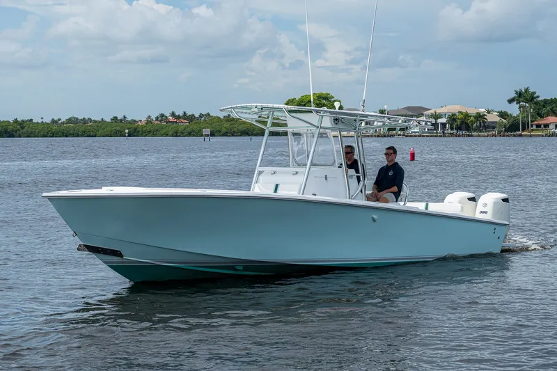 Slide: The Image of 1991 Jupiter 31 Center Console boat cruising on a calm waterway under a partly cloudy sky. - 6