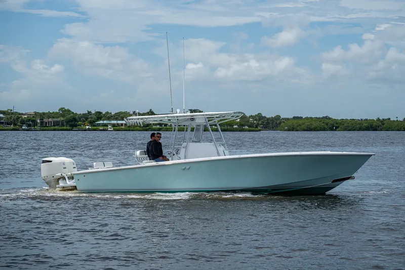 Slide: The Image of 1991 Jupiter 31 Center Console boat cruising on a calm river under a cloudy sky. - 12