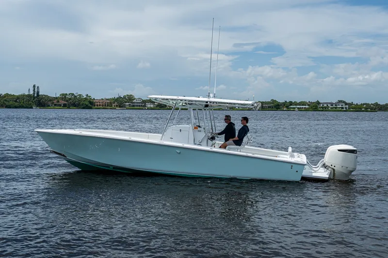 Slide: The Image of 1991 Jupiter 31 Center Console boat cruising on a calm lake under a partly cloudy sky. - 7