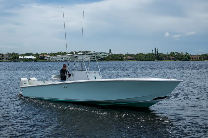 The Image of 1991 Jupiter 31 Center Console boat cruising on a calm lake under a cloudy sky. - 1