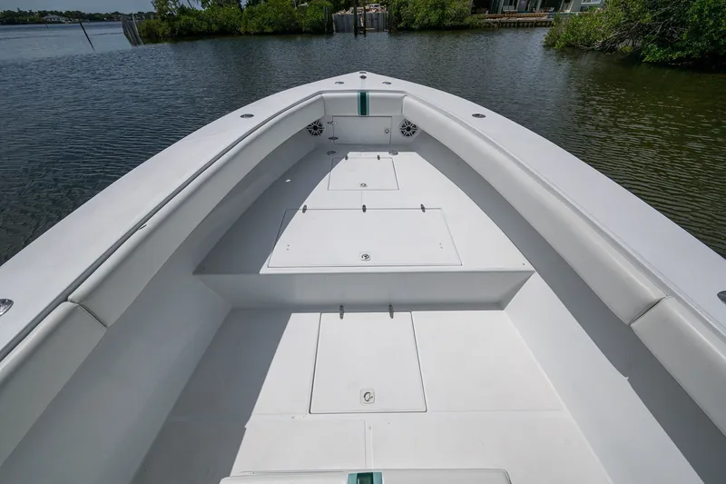 Slide: The Image of 1991 Jupiter 31 Center Console boat, spacious deck, calm waters, lush greenery background. - 36