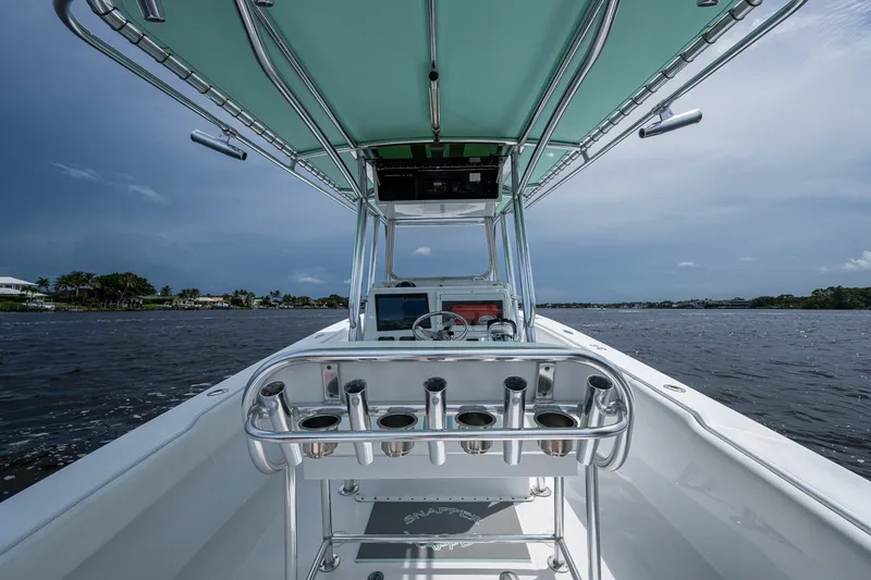 Slide: The Image of 1991 Jupiter 31 Center Console boat on water, featuring rod holders and steering console. - 23