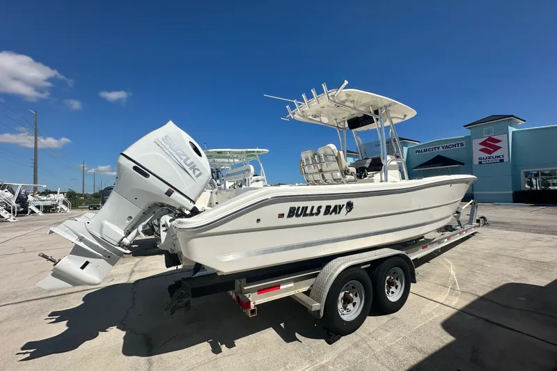Slide: The Image of 2027 Bulls Bay 255 Center Console boat on trailer, Suzuki engine, sunny day at dealership. - 3