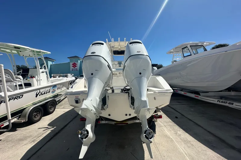 Slide: The Image of 2027 Bulls Bay 255 Center Console boat with dual outboard motors in a marina. - 4