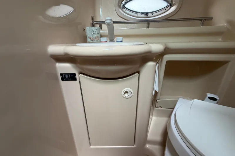 Slide: The Image of 2003 Maxum 2900 SE boat bathroom with sink, toilet, and porthole window. - 81