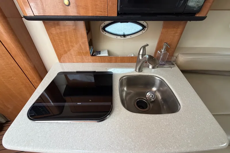 Slide: The Image of Compact kitchen area in a 2003 Maxum 2900 SE boat with sink and stove. - 63