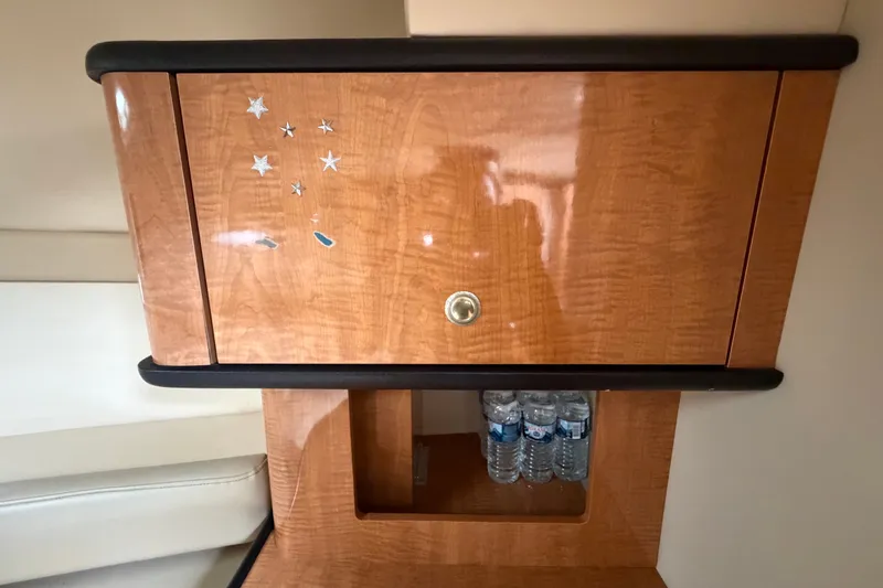 Slide: The Image of Wooden cabinet with star decals and water bottles, inside a 2003 Maxum 2900 SE boat. - 71