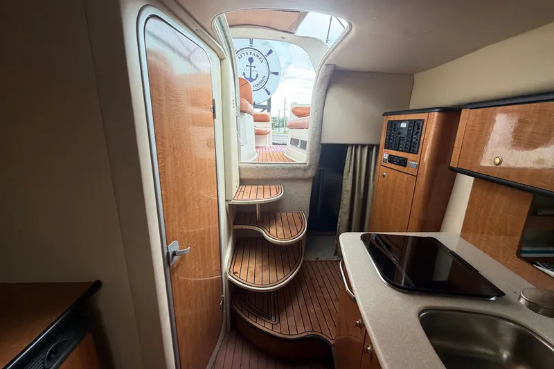 Slide: The Image of 2003 Maxum 2900 SE boat interior with wooden cabinetry and curved stairs. - 76