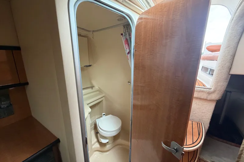 Slide: The Image of 2003 Maxum 2900 SE boat interior showing compact bathroom with toilet and wooden door. - 77
