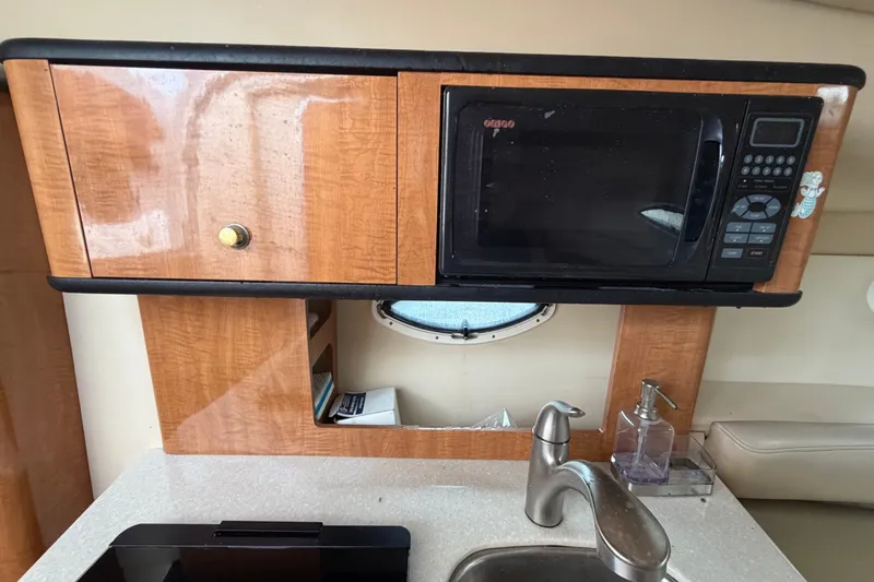Slide: The Image of 2003 Maxum 2900 SE boat kitchen with microwave, wooden cabinets, and sink. - 61