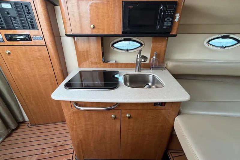 Slide: The Image of 2003 Maxum 2900 SE boat interior with kitchenette, featuring sink, stove, and microwave. - 60