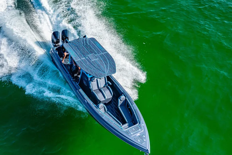 Slide: The Image of 2025 Glasstream 32 GSX speeding on vibrant green water, aerial view. - 1