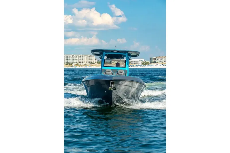 Slide: The Image of 2025 Glasstream 32 GSX boat cruising on open water with coastal buildings in background. - 13