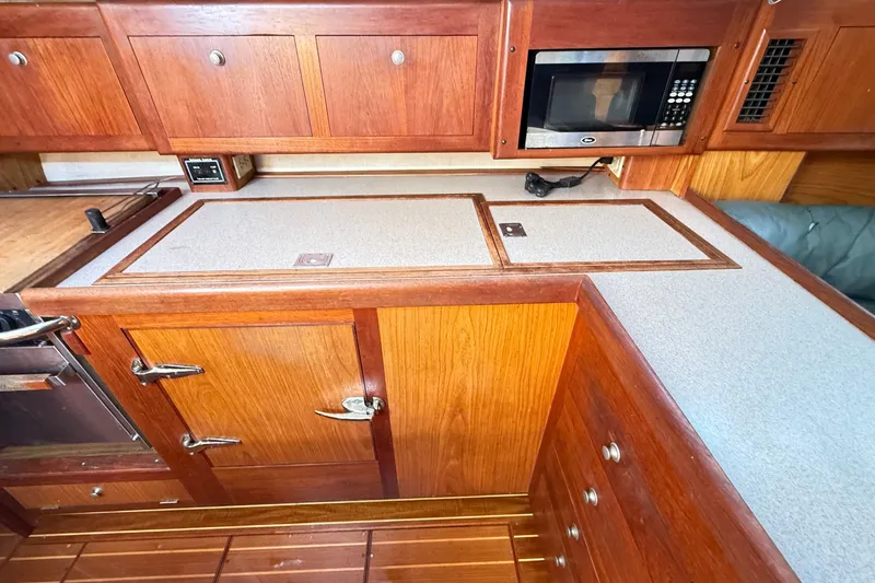 Slide: The Image of Wooden kitchen interior of a 2000 Hunter 460 yacht with microwave and cabinets. - 32