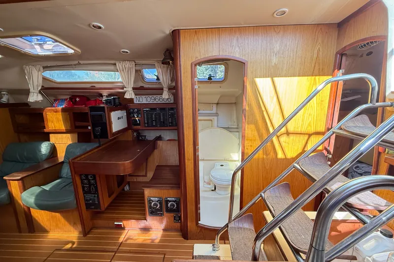 Slide: The Image of Interior of a 2000 Hunter 460 sailboat featuring wood paneling and a compact bathroom. - 37