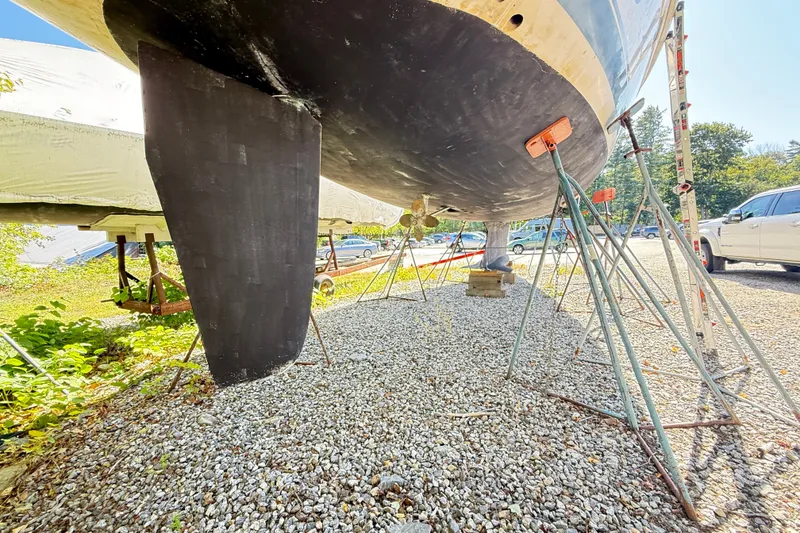 Slide: The Image of Hunter 460 sailboat from 2000 on stands, showing keel and propeller, parked on gravel. - 74