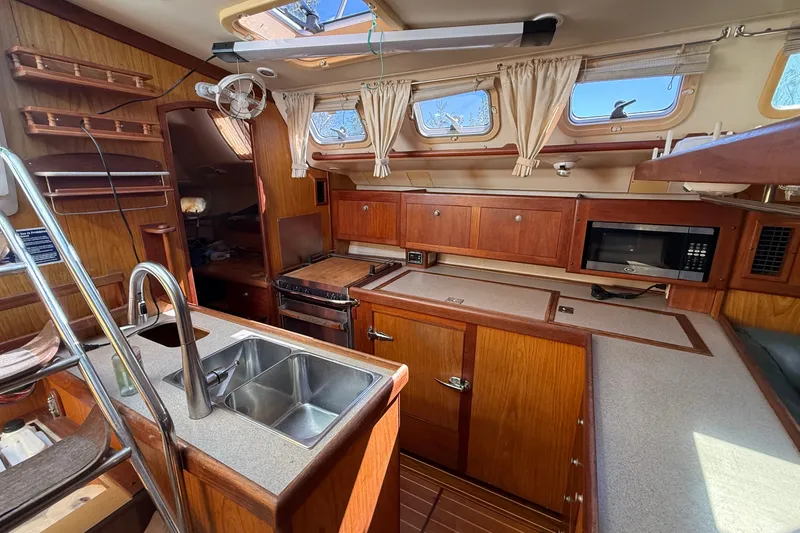 Slide: The Image of Interior of a 2000 Hunter 460 yacht kitchen with wood cabinetry and modern appliances. - 27