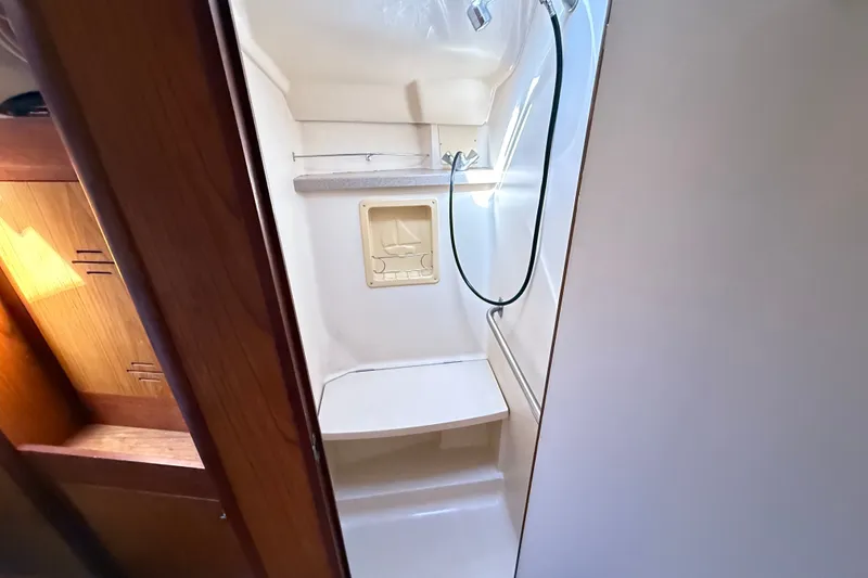 Slide: The Image of Compact shower area in a 2000 Hunter 460 sailboat, featuring a built-in seat and showerhead. - 61
