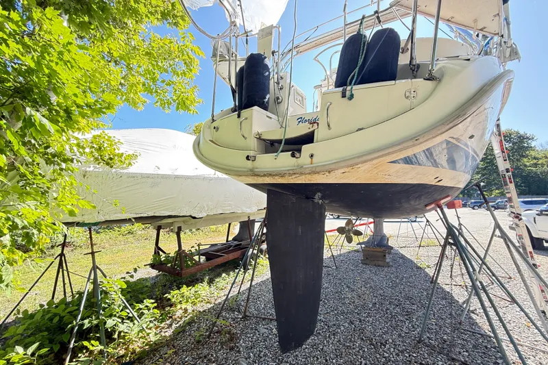 Slide: The Image of 2000 Hunter 460 sailboat on stands, surrounded by trees and gravel. - 73