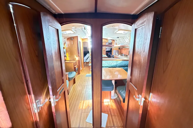 Slide: The Image of Interior view of 2000 Hunter 460 yacht, featuring wooden cabinetry and cozy seating area. - 52