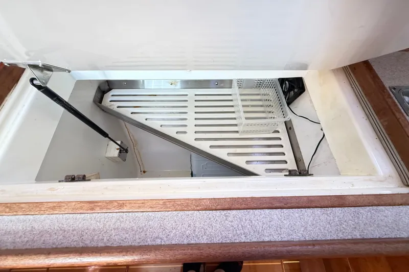 Slide: The Image of Open storage compartment in a 2000 Hunter 460 boat, featuring a metal rack and basket. - 33