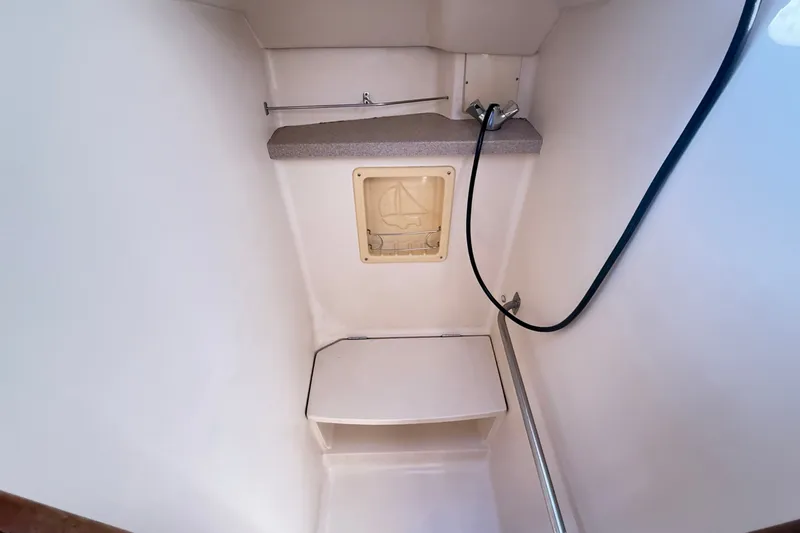 Slide: The Image of Compact shower area in a 2000 Hunter 460 sailboat, featuring a bench and handheld showerhead. - 62
