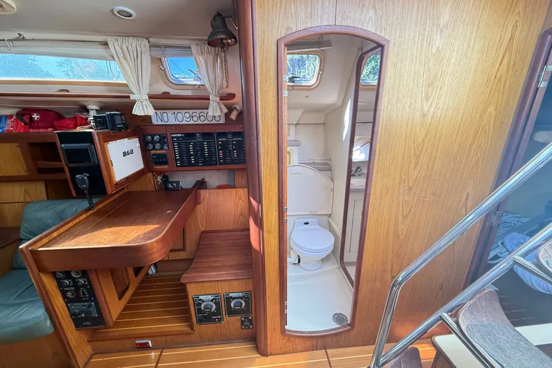 Slide: The Image of Interior of a 2000 Hunter 460 sailboat featuring a navigation station and compact bathroom. - 41