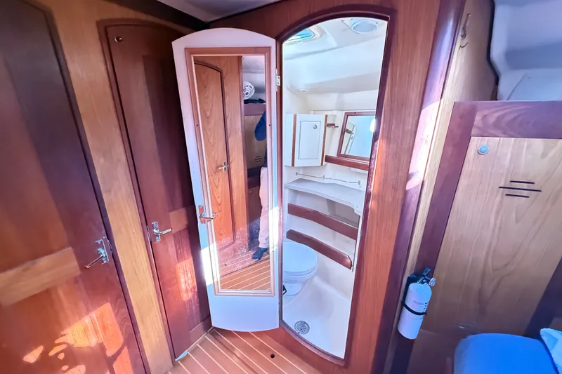 Slide: The Image of Interior of a 2000 Hunter 460 yacht featuring a compact bathroom with wooden accents. - 57