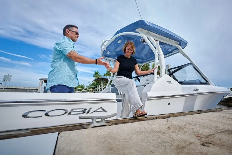 Slide: The Image of Couple stepping off a 2027 Cobia 250 Dual Console boat at a dock. - 16