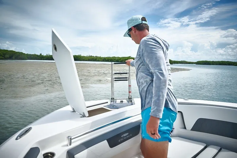 Slide: The Image of Man on 2027 Cobia 250 Dual Console boat adjusting ladder near shore. - 18