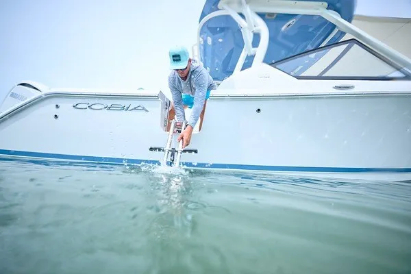 Slide: The Image of 2027 Cobia 250 Dual Console boat on water, person adjusting anchor. - 17