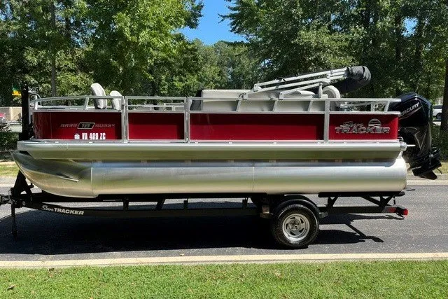 Slide: The Image of 2026 Sun Tracker Bass Buggy 18 DLX pontoon boat on trailer, parked outdoors. - 18