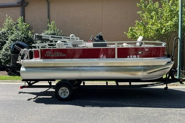 The Image of 2026 Sun Tracker Bass Buggy 18 DLX pontoon boat on trailer, parked outdoors. - 1