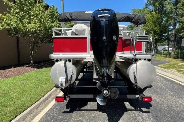 Slide: The Image of 2026 Sun Tracker Bass Buggy 18 DLX pontoon boat, rear view with motor, parked outdoors. - 16