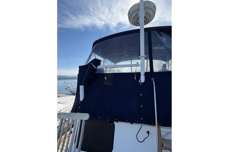 Slide: The Image of 1979 Ocean Alexander 40 Double Cabin yacht with blue canopy and radar, docked under clear skies. - 58