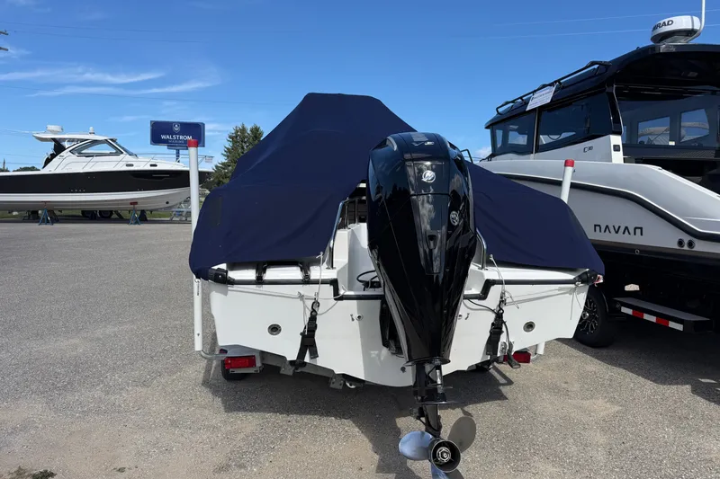 Slide: The Image of 2000 Boston Whaler 21 Outrage boat with cover and outboard motor in a dealership lot. - 18