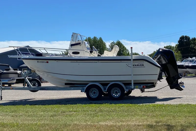 The Image of 2000 Boston Whaler 21 Outrage boat on trailer, parked outdoors under clear sky. - 0